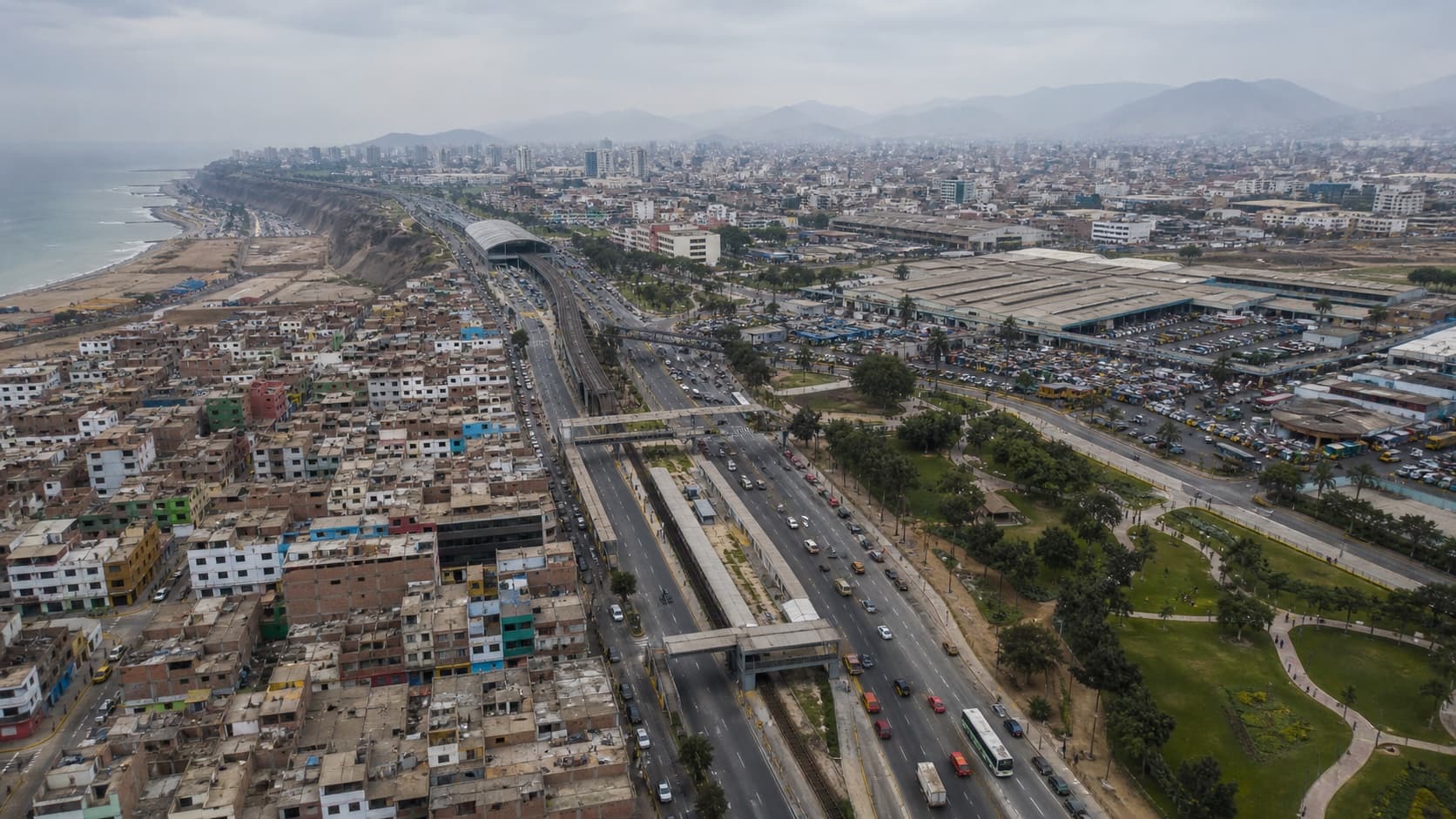 Vista elevada de una ciudad costera peruana atravesada por infraestructura metropolitana